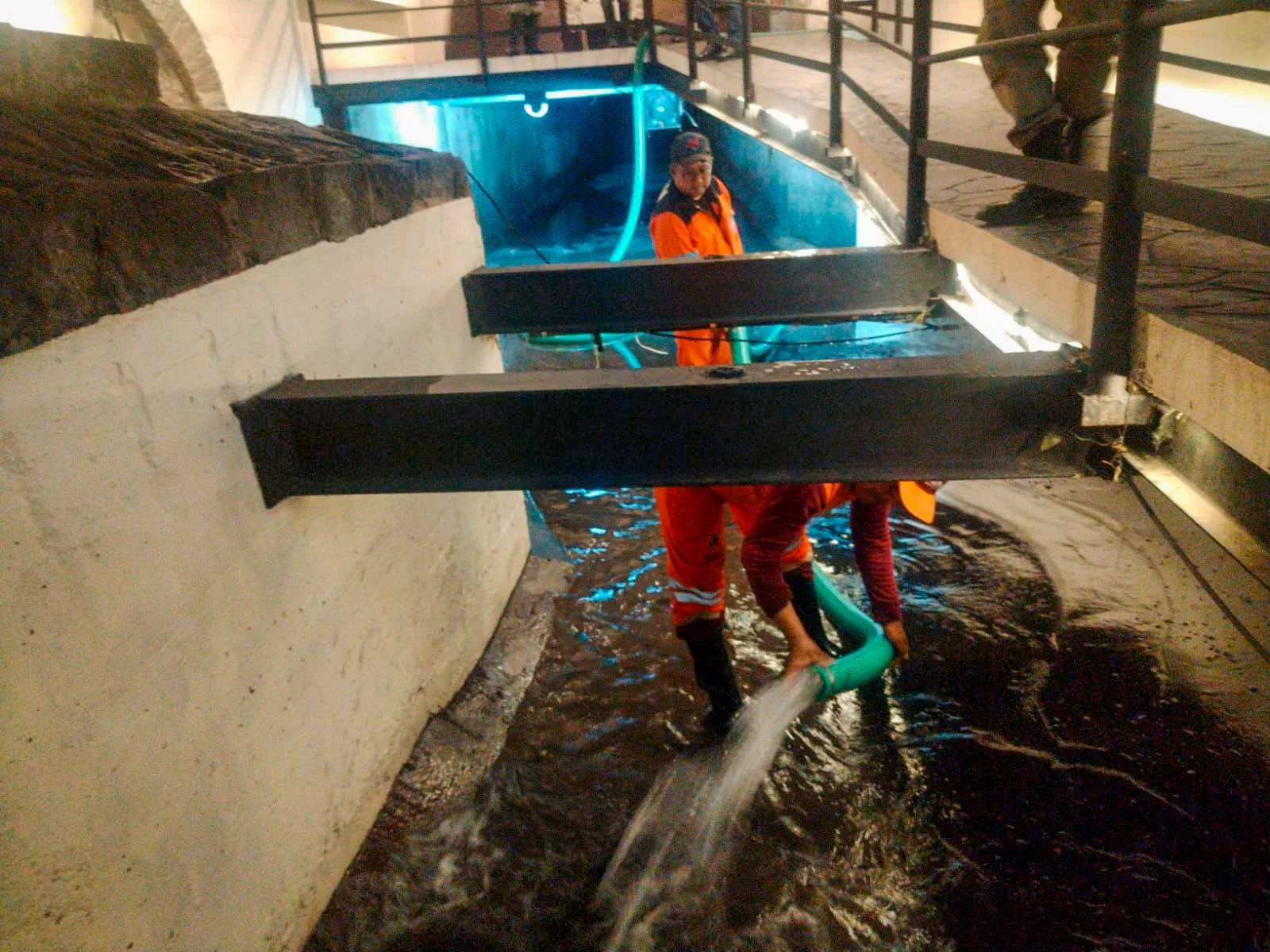 Personal de Limpia con uniforme naranja lava el Puente de Bubas con manguera tras la lluvia en Puebla.